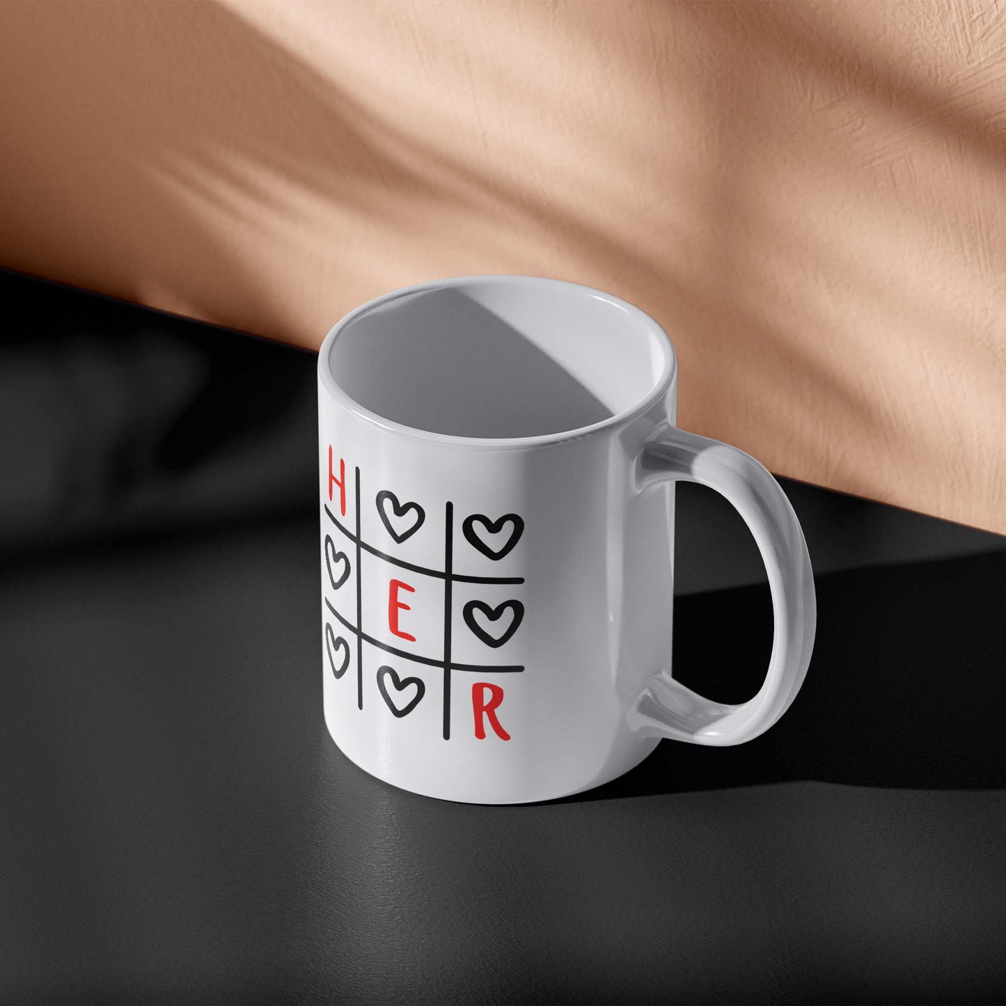 White mug with 'HER' design on a dark surface