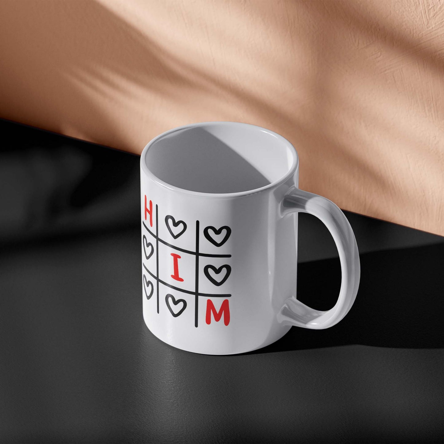 White mug with 'HIM' design on a dark surface